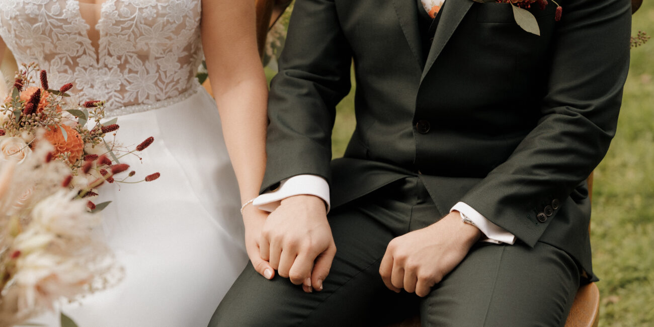 Brautpaar hält sich an den Händen während Trauung